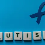 Colorful dice spelling 'AUTISM' on a blue background, highlighting levels of autism