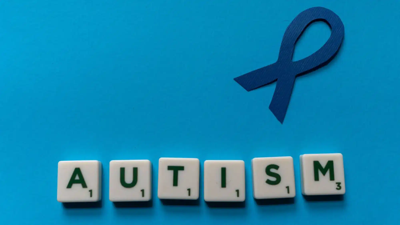 Colorful dice spelling 'AUTISM' on a blue background, highlighting levels of autism